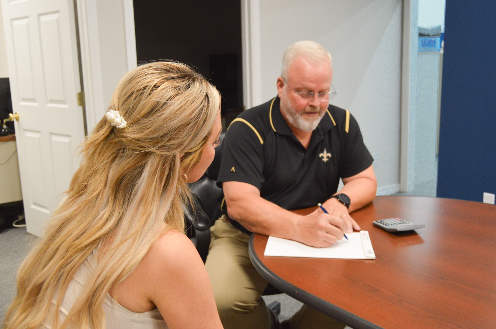 A man is signing documents while a woman observes attentively in a professional setting.